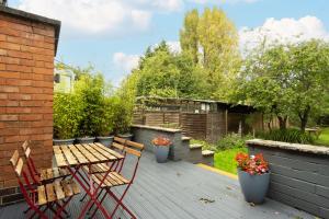 a deck with a wooden table and chairs and flowers at Stratford House in Leicester