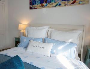 uma cama com almofadas azuis e brancas e uma almofada de boa noite em Avocet House Hunstanton 250m from the sea em Hunstanton