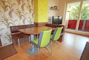 una sala da pranzo con tavolo in legno e sedie verdi di Apart 15 by Alpenidyll Apartments a Schladming