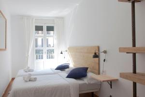 Un dormitorio con una cama con almohadas azules y una ventana en My Address in Sant Antoni en Barcelona