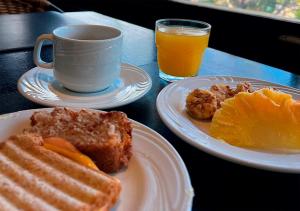 a table with two plates of food and a cup of orange juice at Blue Tree Thermas de Lins Resort in Lins