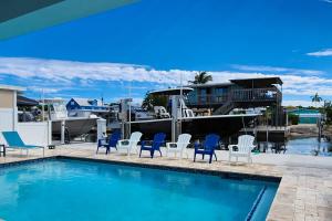 a pool with blue and white chairs and a boat at Afternoon Delight in Key Largo