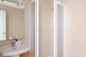 La salle de bains blanche est pourvue d'un lavabo et d'une douche. dans l'établissement My Address in Sant Antoni, à Barcelone