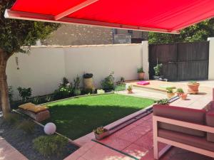 a small backyard with a red umbrella and a lawn at La Coccinelle in Nîmes