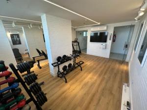 a gym with dumbbells and a flat screen tv at Quarto plus no Linhares Design Hotel ES in Linhares