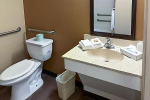 a bathroom with a toilet and a sink with a mirror at Suburban Studios Houston North I-45 in Houston