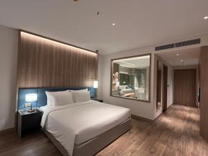 a bedroom with a large white bed and a mirror at Căn hộ khách sạn Alacarte Hạ Long in Ha Long