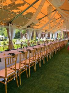 uma longa linha de mesas e cadeiras sob uma tenda em Vila Forest Resort 