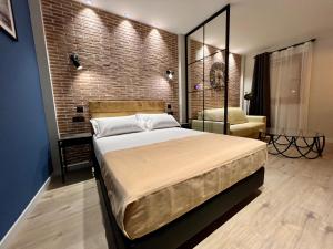 a bedroom with a large bed and a brick wall at Aparthotel Luz de Gades - Suites Spa Gym - Adults Only in Cádiz