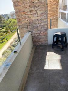 a stool sitting on a balcony next to a brick wall at Hermoso depto Lomas de Papudo 2 in Papudo