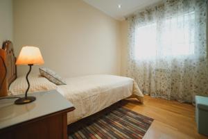 a bedroom with a bed with a lamp and a window at Praza do Concello The Way in Negreira