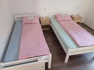 two twin beds in a room with two tables at Sobe Kata - atomska banja Gornja Trepca in Čačak