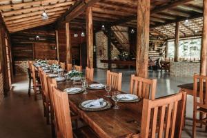 a long wooden table with chairs and plates and wine glasses at Fazenda Momm - Pousada e Eventos in Camboriú