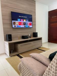 uma sala de estar com uma televisão de ecrã plano na parede em Apartamento Aconchego Carapibus em Conde