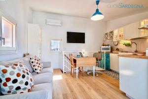 a living room and kitchen with a couch and a table at ClickSardinia Alghero historic centre cosy penthouse with sea view terrace in Alghero
