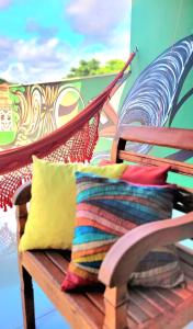 um banco de madeira com almofadas sobre ele com um mural em Praieira Hostel&Pousada em Itacaré