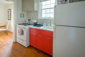 eine Küche mit roten Schränken und einem weißen Kühlschrank in der Unterkunft Retro Bungalow A Block to Tennis Courts & Park in Richmond