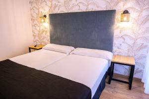 a bedroom with a large bed with white sheets at Complejo Roma in Aldeanueva del Camino
