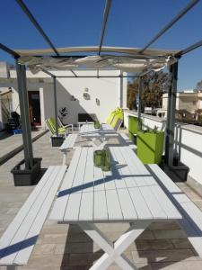 un patio con mesas blancas y sillas en la azotea en Le casette di Frà Studios, en Santa Severa