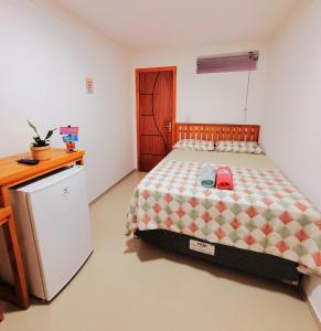 um quarto com uma cama, uma secretária e um frigorífico em Praieira Hostel&Pousada em Itacaré