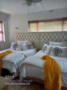 ケープタウンにあるTurning Point B&Bのベッドルーム1室(白いシーツとヘッドボード付きのベッド2台付)