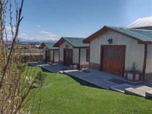 a row of buildings in a yard with grass at Cabañas Ventalia in El Calafate