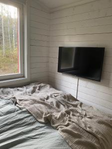 an unmade bed with a flat screen tv on a wall at Peaceful and Scandinavian-style Guesthouse with Scenic Nature and Seaview in Domsjö