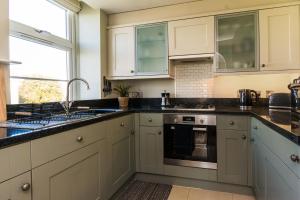 a kitchen with white cabinets and black counter tops at Stunning Sea View Central Torbay Home with Parking in Torquay