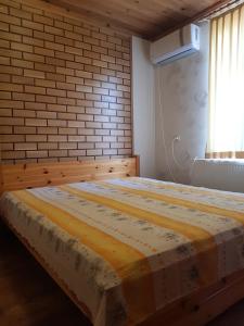 Ce lit se trouve dans une chambre dotée d'un mur en briques. dans l'établissement Wine Boutique Complex ,,Hrisimov", à Musomishta