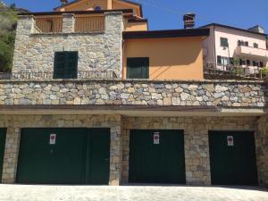 a stone building with four green garage doors at Estate Riomaggiore in Riomaggiore