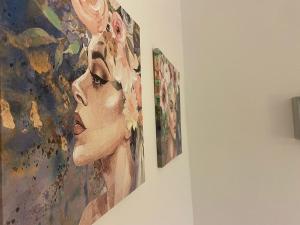 dos pinturas de una mujer colgando de una pared en Le casette di Frà Studios en Santa Severa
