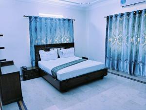 a bedroom with a large bed with blue curtains at Karachi Family Guest House in Karachi