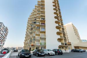 a parking lot with cars parked in front of a tall building at BnB Homes Praia da Rocha Beach Bright Apartment 50 m away from the ocean in Portimão