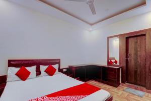 een slaapkamer met een bed met rode kussens en een spiegel bij Flagship Hotel Days Inn in Rānchī