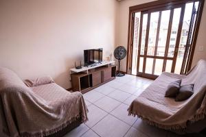 a room with two beds and a tv and a window at Condomínio Familiar - Aptos Novos e Completos in Nova Petrópolis