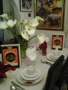 un tavolo con piatti e un vaso con fiori bianchi di Turning Point B&B a Città del Capo