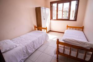 two beds in a room with a window at Condomínio Familiar - Aptos Novos e Completos in Nova Petrópolis