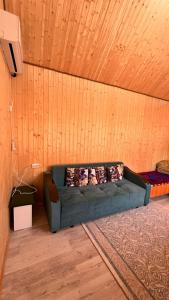 a green couch in a room with a wooden wall at Eldos_Kolsai in Saty