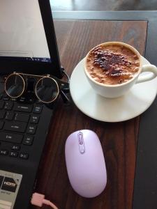a cup of coffee on a desk next to a laptop at Studio Healing Sayana Apartment in Tambun-lobangbuaja