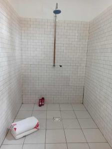 a white tiled shower with a towel on the floor at Bosofet Beach and Creek Lodge in Sanyang