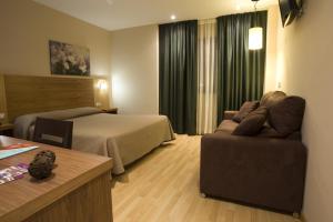 um quarto de hotel com uma cama e um sofá em Hotel Mar de Plata em Sarria