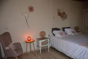 una camera con letto, sedia e candela di LE HOME FLEURI MLD a Ménesplet