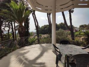a table and chairs on a patio with palm trees at Villa Muia-Appartamento con ampio terrazzo in Parabita +14 photos