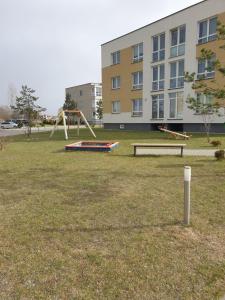 a park with two swings and a playground at Family apartment in Kretinga