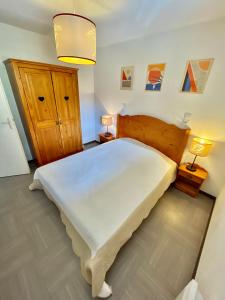 a bedroom with a large white bed with two lamps at Appartement sur les pistes de ski avec piscine in Sainte-Marie-de-Vars