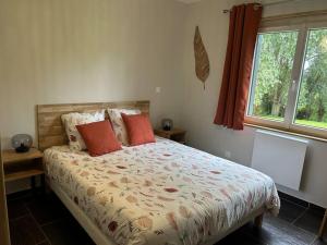 a bedroom with a bed with orange pillows and a window at La Héronnière - gîte de groupe in Houlle