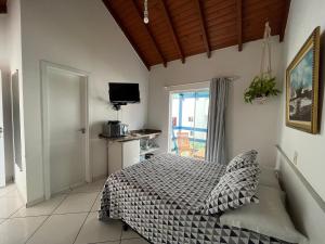 1 dormitorio con 1 cama y TV en Pousada Canario Azul, en Bombinhas