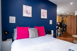 a blue bedroom with a white bed with pink pillows at REEF9 - Modern central flat, 5 mins from beach, centre and Bournemouth International Centre in Bournemouth