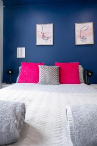 a bedroom with blue walls and a bed with pink pillows at REEF9 - Modern central flat, 5 mins from beach, centre and Bournemouth International Centre in Bournemouth