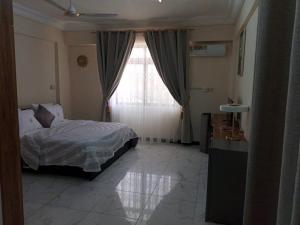 um quarto com uma cama e uma grande janela em Edgard Hotel em Accra